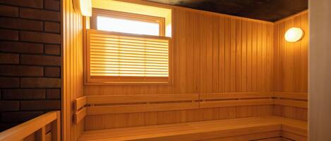 A sauna with wooden benches and a window with blinds.