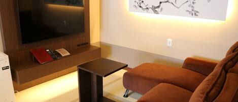 A modern living room with a flat-screen TV, a small table, and a sofa.