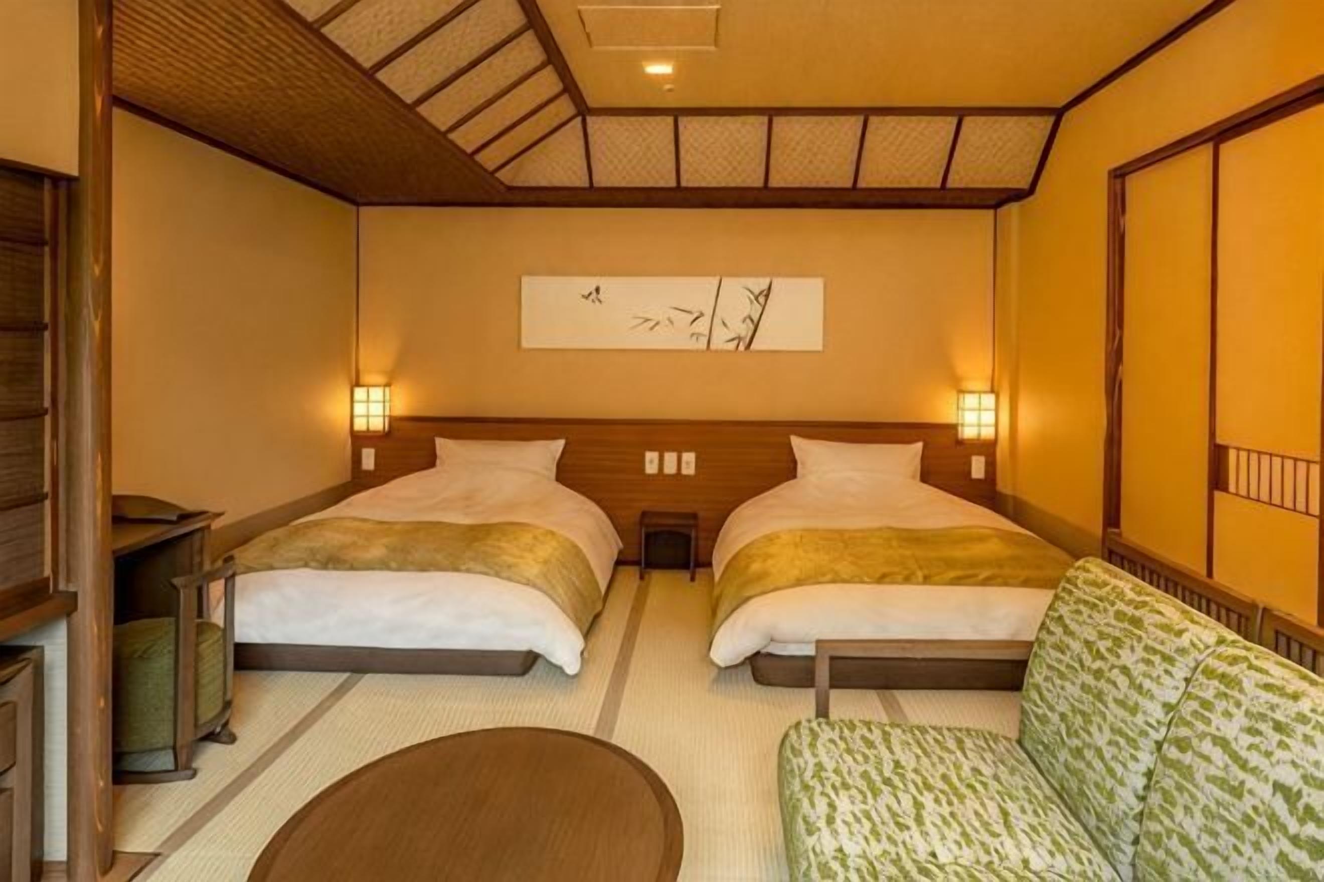 Een hotelkamer met twee bedden, een bank, een tatami mat en een kunstwerk aan de muur.