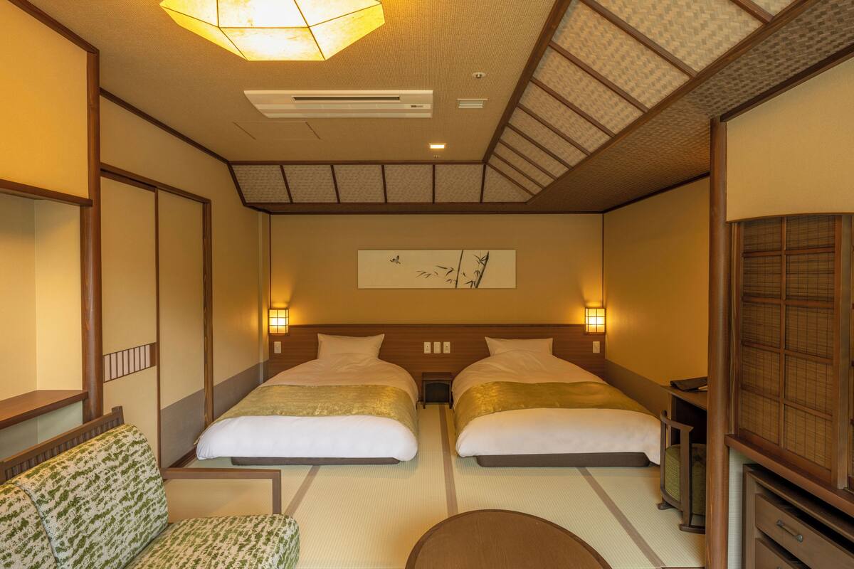 Ein Hotelzimmer mit zwei Betten, einem Schlafsofa, einem kleinen Tisch und einem Wandbild.
