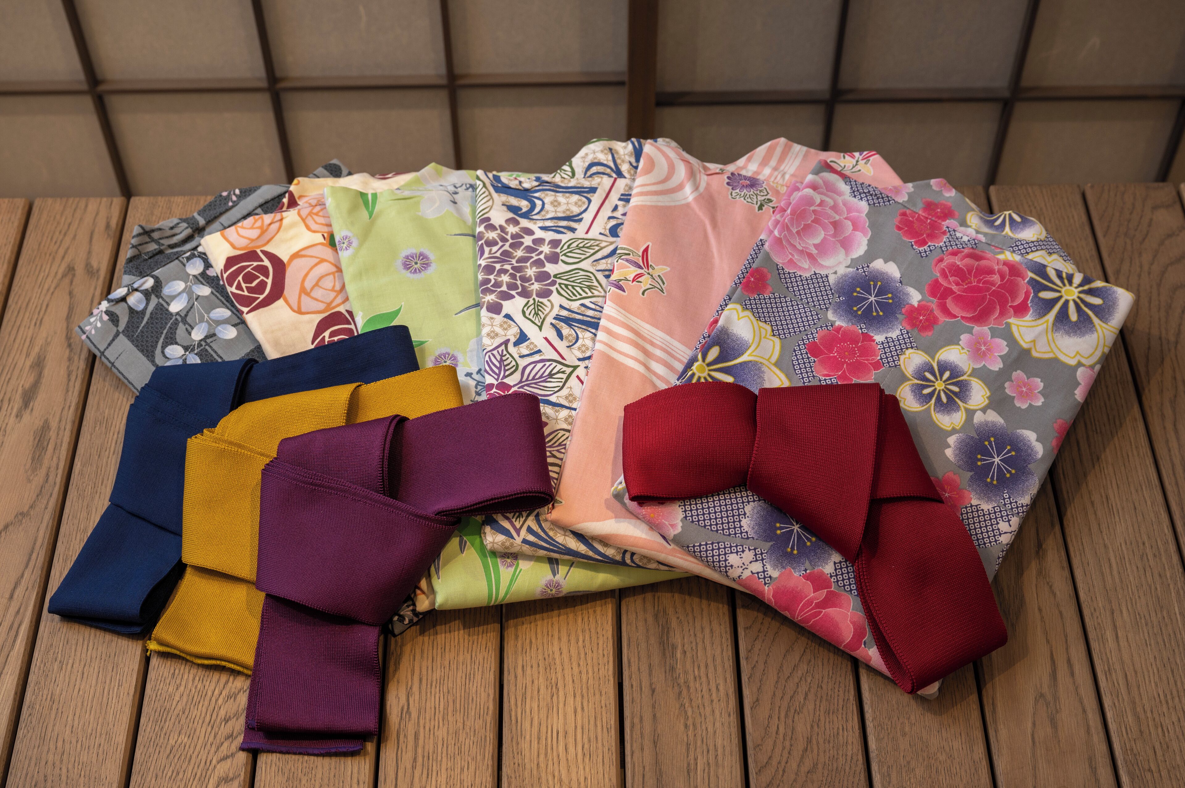 A variety of colorful fabrics laid out on a wooden surface.