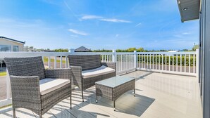 A covered outdoor seating area with wicker furniture and a view of the surrounding landscape. - Platinum Caravan 6 Berth (3 bed) (Pet) (Skegness)