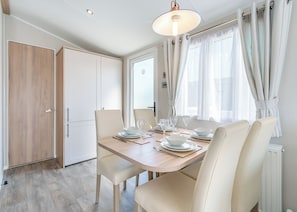 A dining area with a wooden table, white chairs, and a hanging light fixture.