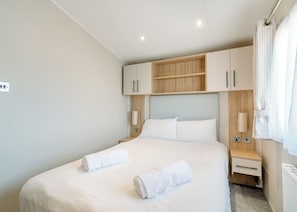 Quarto de hotel moderno com cama grande, cabeceira de madeira, mesas de cabeceira e armário embutido.