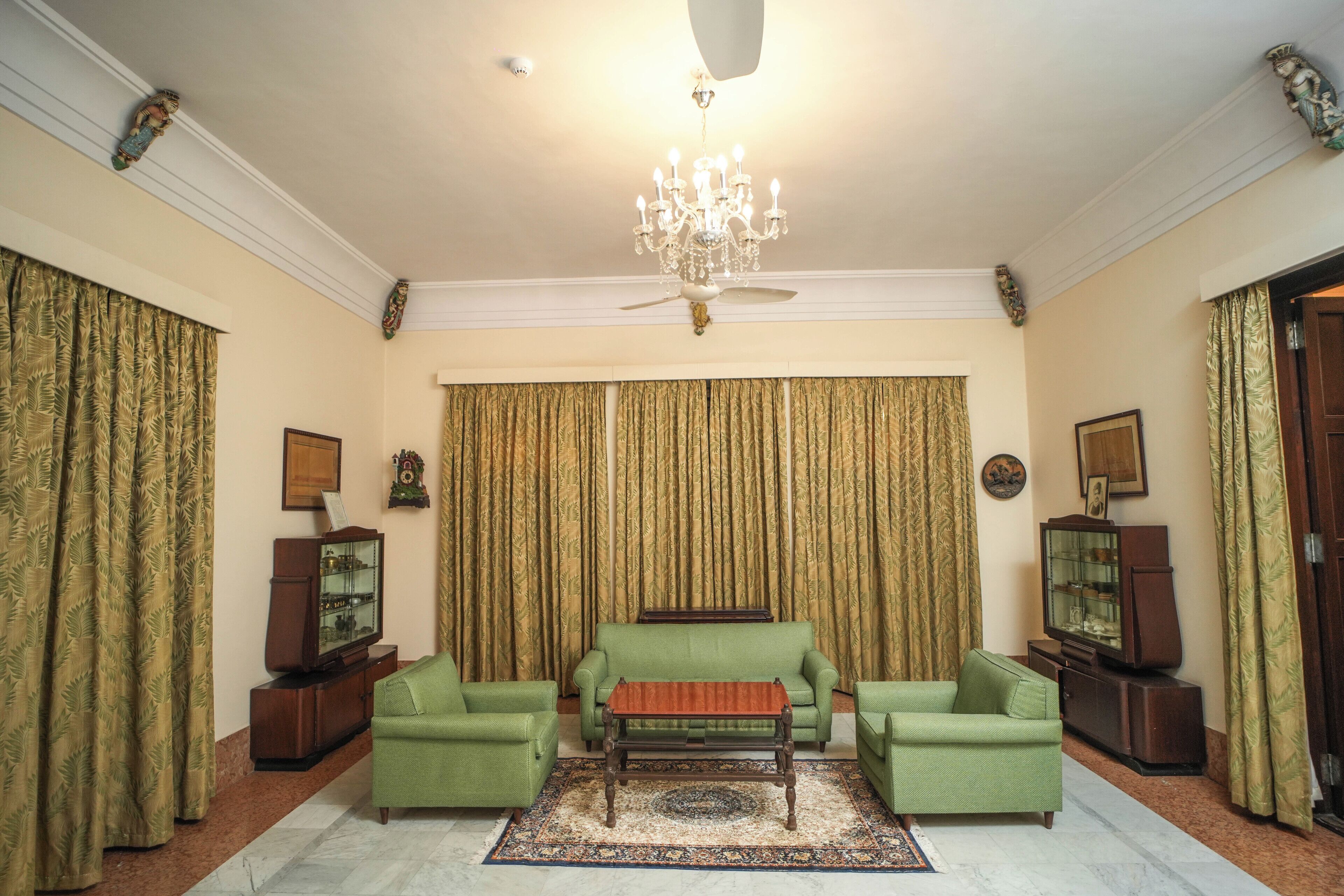 A living room with a green sofa, a wooden coffee table, and a chandelier.