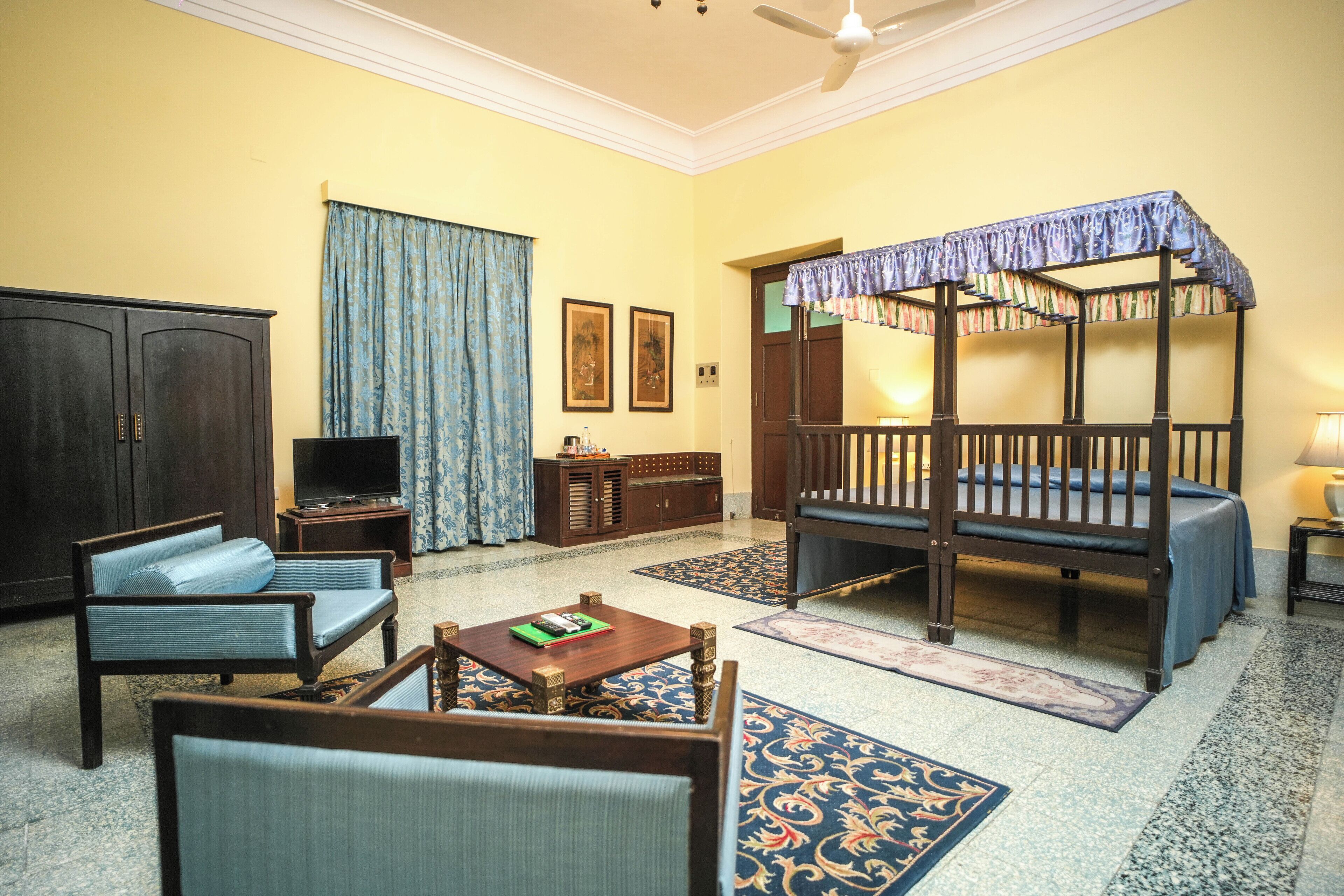 A traditional room with a four-poster bed, a television, and a sofa.
