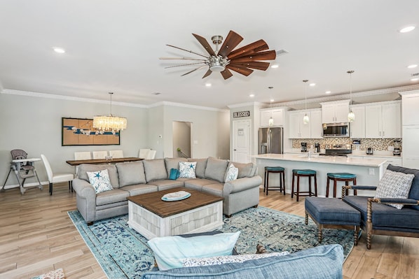 A modern living room with a sectional sofa, a coffee table, and a dining area.