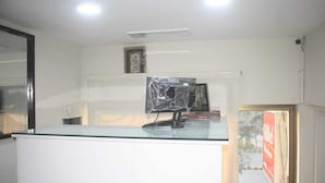 A reception desk with a glass top, a computer monitor, and a framed picture on the wall. - Hotel Shadman (Lahore)