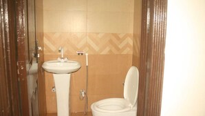 A small bathroom with a toilet, a sink, and a shower. - Hotel Shadman (Lahore)