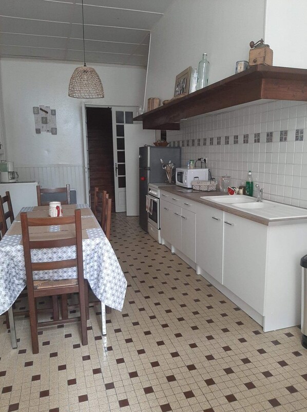 Une cuisine équipée d’une table à manger, de chaises, d’un four à micro-ondes, d’un réfrigérateur et d’un évier.