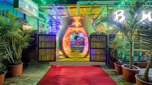 Una entrada llamativa con una alfombra roja que conduce a un arco iluminado con neón.