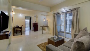 Una sala de estar con televisión, sofá, mesa de centro y vistas al exterior a través de un ventanal.