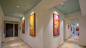 A hallway with marble flooring, two doors, and three large abstract paintings on the walls. - Apex Beacon Hotel, Mumbai (Mumbai)