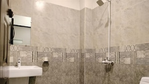 Et badeværelse med bruser, toilet og håndvask.