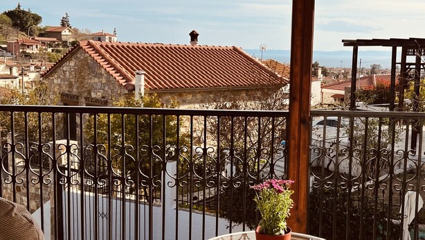 Un balcone con sedie in vimini, un tavolino in vetro e una pianta in vaso.