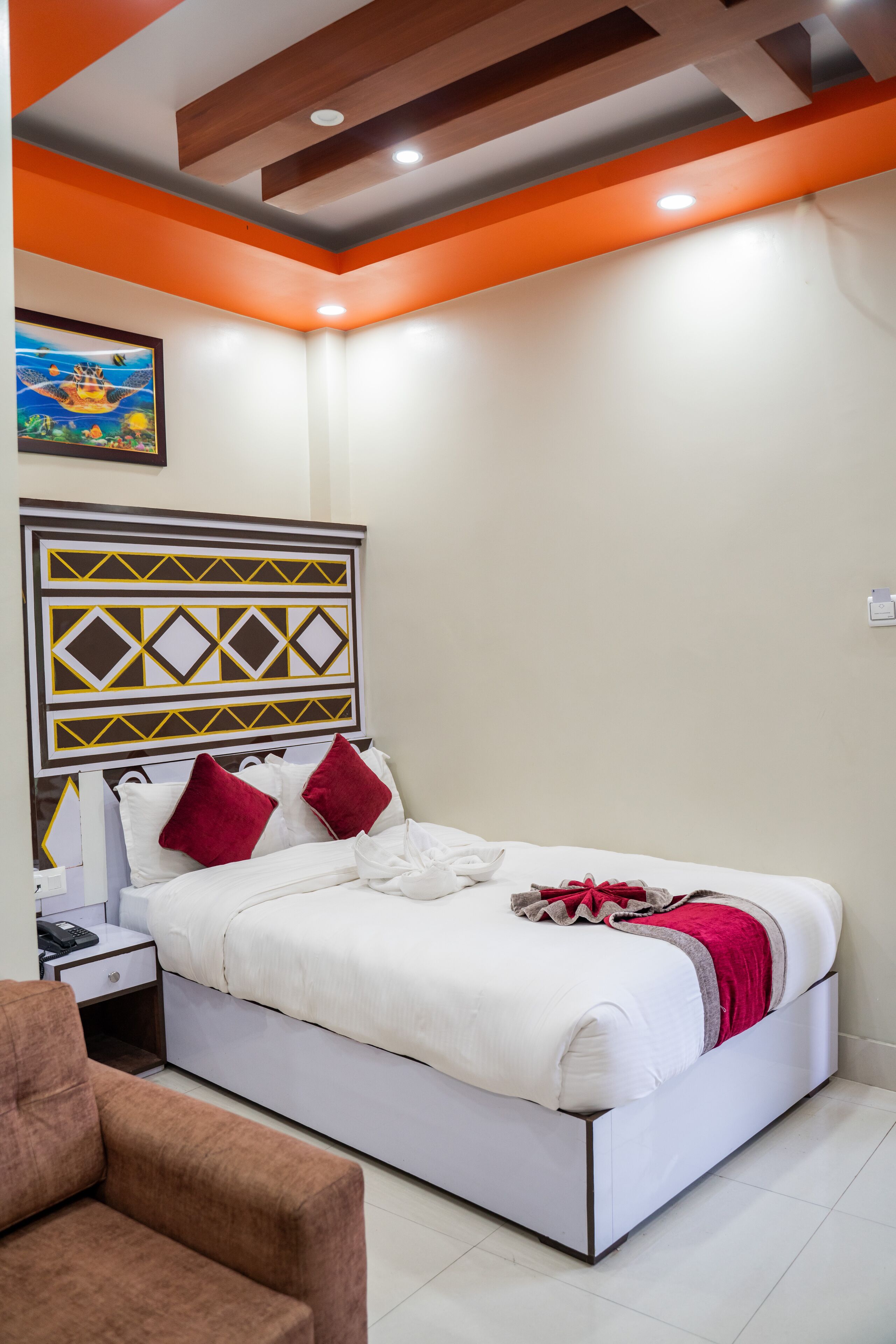 Een moderne hotelkamer met een wit bed, rode kussens en een decoratief hoofdeinde.