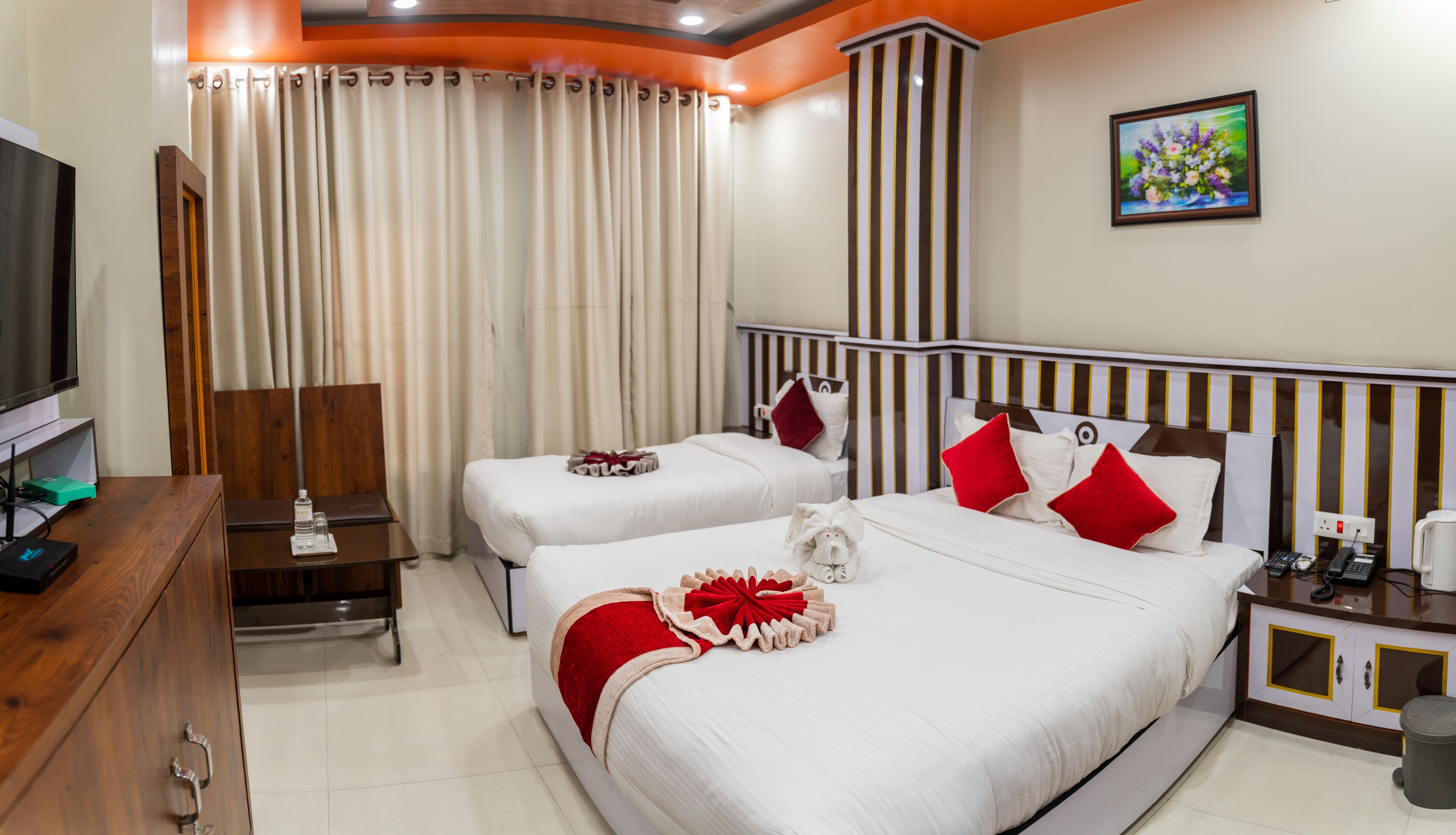 A hotel room with two beds, a TV, a desk, and a bathroom.
