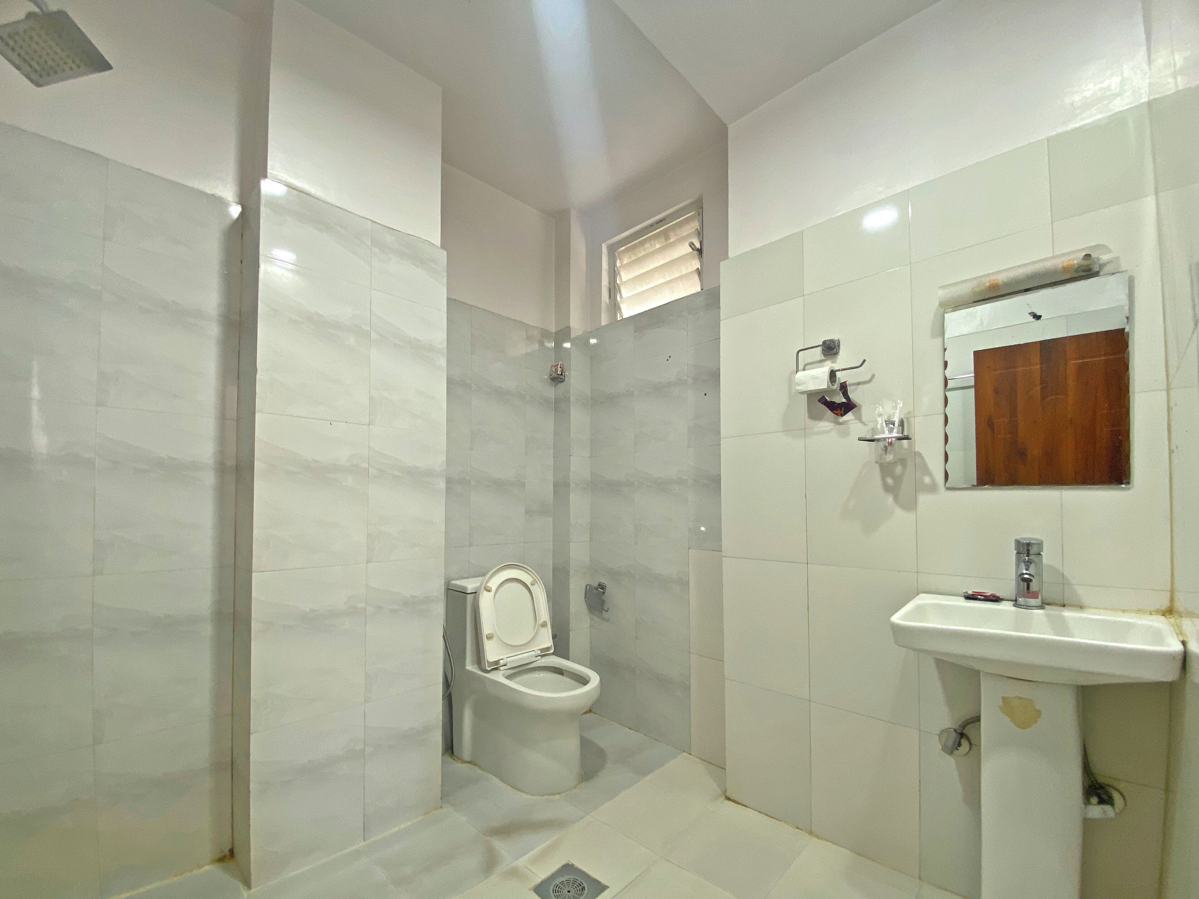 Une salle de bain comprenant des toilettes, un lavabo et un espace douche.