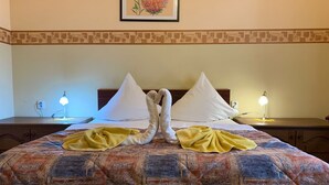 A hotel room with a bed featuring a decorative headboard, two bedside lamps, and a framed floral artwork on the wall. - Hotel Victor  (Prague)