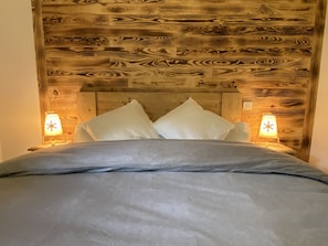 A bed with a wooden headboard, two bedside lamps, and a grey bedspread.