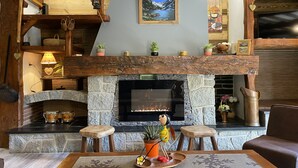 Una chimenea acogedora con paredes de piedra, vigas de madera y un repisa con adornos.