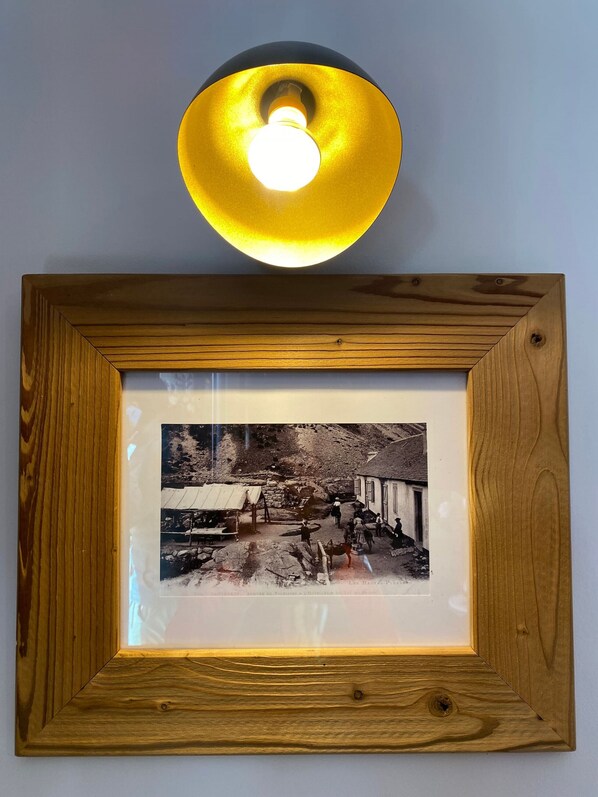 A framed photograph with a wooden border and a light fixture above it.