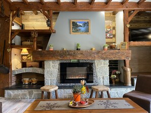 A cozy fireplace area with a stone surround, wooden beams, and a mounted painting.