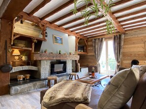 A rustic interior with a stone fireplace, wooden beams, and a cozy seating area.