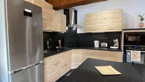 Una cocina moderna con electrodomésticos de acero inoxidable, gabinetes de madera y una encimera negra.