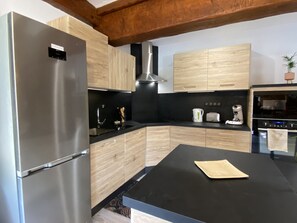 A modern kitchen with stainless steel appliances, wooden cabinets, and a black countertop.