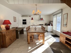Una cocina moderna con comedor, que incluye una mesa de madera, sillas y una araña.