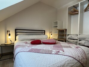 Makuuhuoneessa on sänky, yöpöytälamput, vaatekaappi ja pieni puinen hylly.