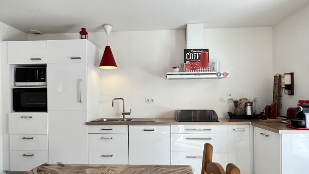Una cocina moderna con armarios blancos, microondas, horno y cafetera.
