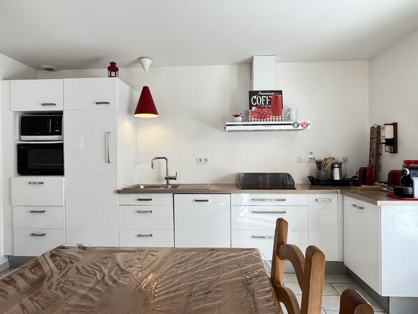 Una cocina moderna con armarios blancos, microondas, horno y cafetera.