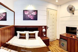 Habitación de hotel con cama, televisión, minibar y obras de arte en la pared.