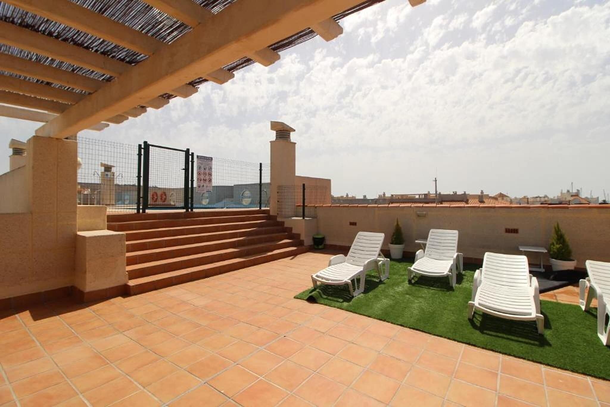 A rooftop terrace with outdoor seating, a staircase, and a view of the cityscape.