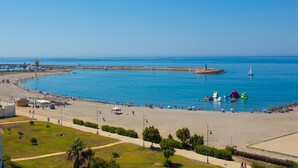 Una playa costera con un mar azul transparente, una orilla arenosa y algunas embarcaciones.