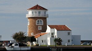 Un faro con torre de ladrillo y un edificio blanco con tejado rojo.