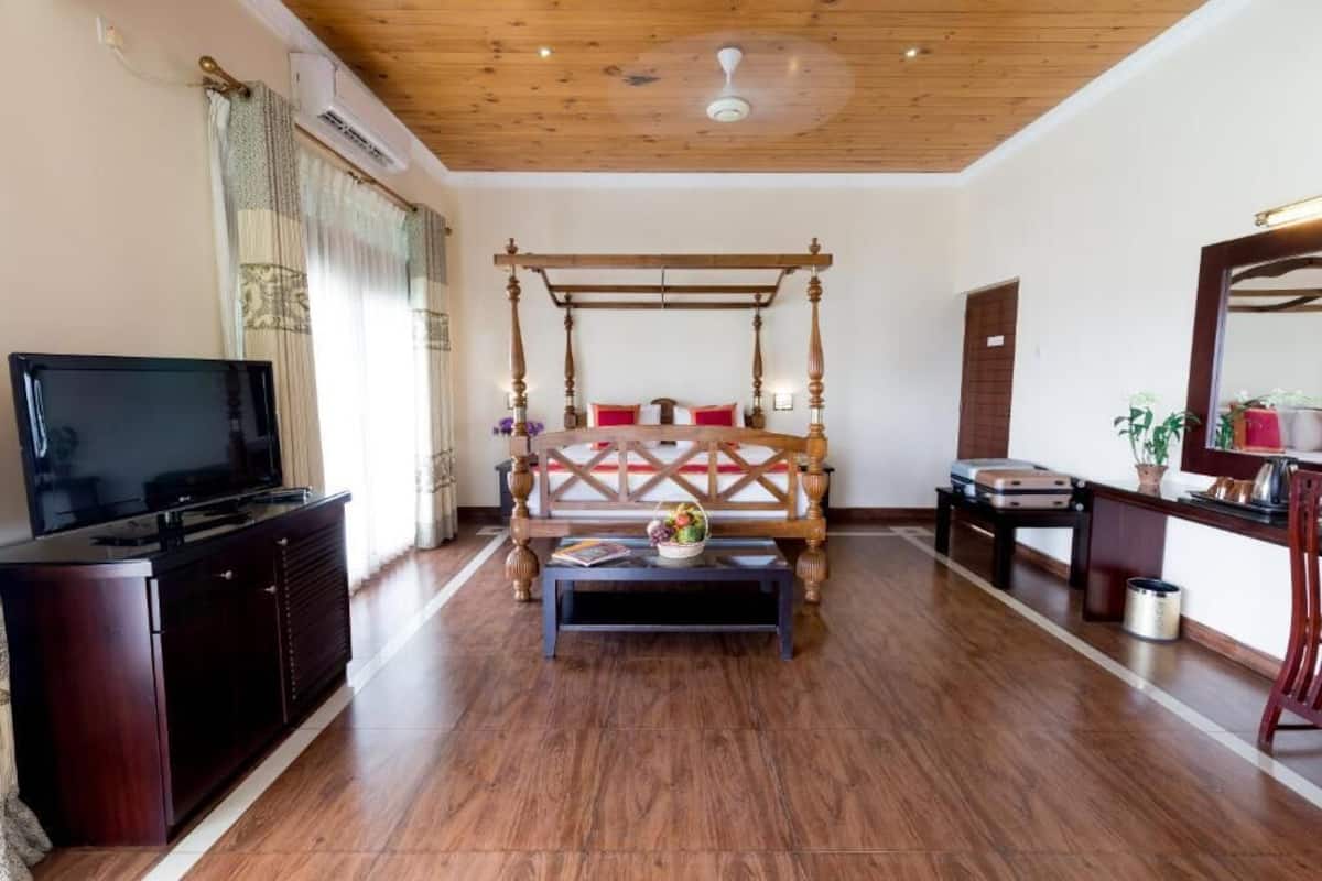 A bedroom with a wooden four-poster bed, a television on a cabinet, and a small table with a basket.