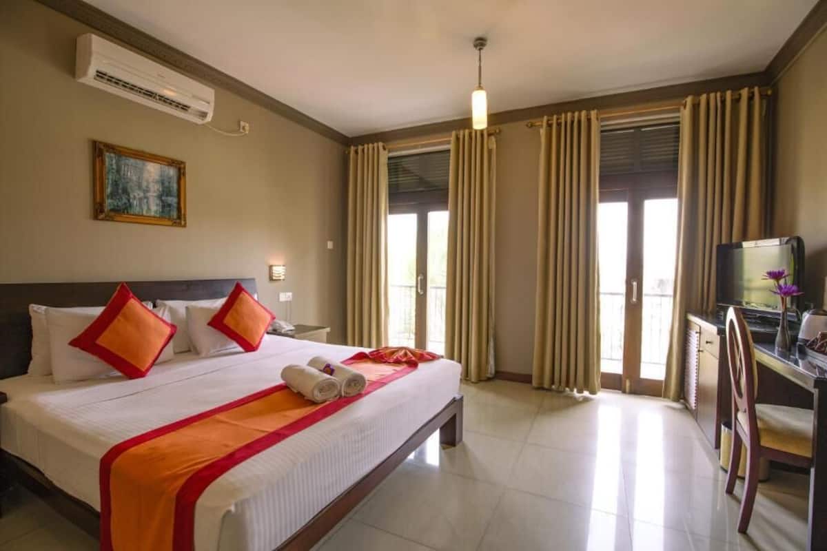 A hotel room with a large bed, a desk with a computer, and a television.