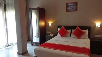 Habitación de hotel con cama, dos lámparas de noche, mesita de noche, armario y un cuadro en la pared.