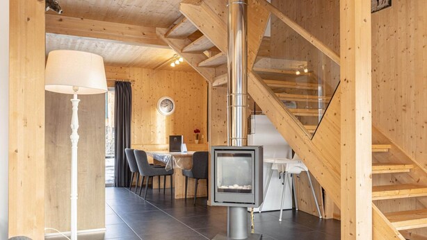 A wooden interior with a central fireplace, a staircase, and a dining area. - Spacious chalet with IR Sauna and whirlpool (Murau)