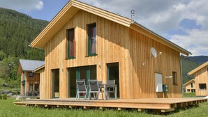 A wooden cabin with a balcony, a table, and chairs. - Spacious chalet with IR Sauna and whirlpool (Murau)