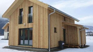 A wooden cabin with a sloped roof, large windows, and a covered porch area. - Spacious chalet with IR Sauna and whirlpool (Murau)