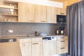 A modern kitchen with wooden cabinets, a built-in microwave, and a coffee maker.