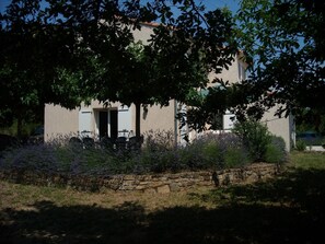 A house with a stone wall in front, a door, and a window.