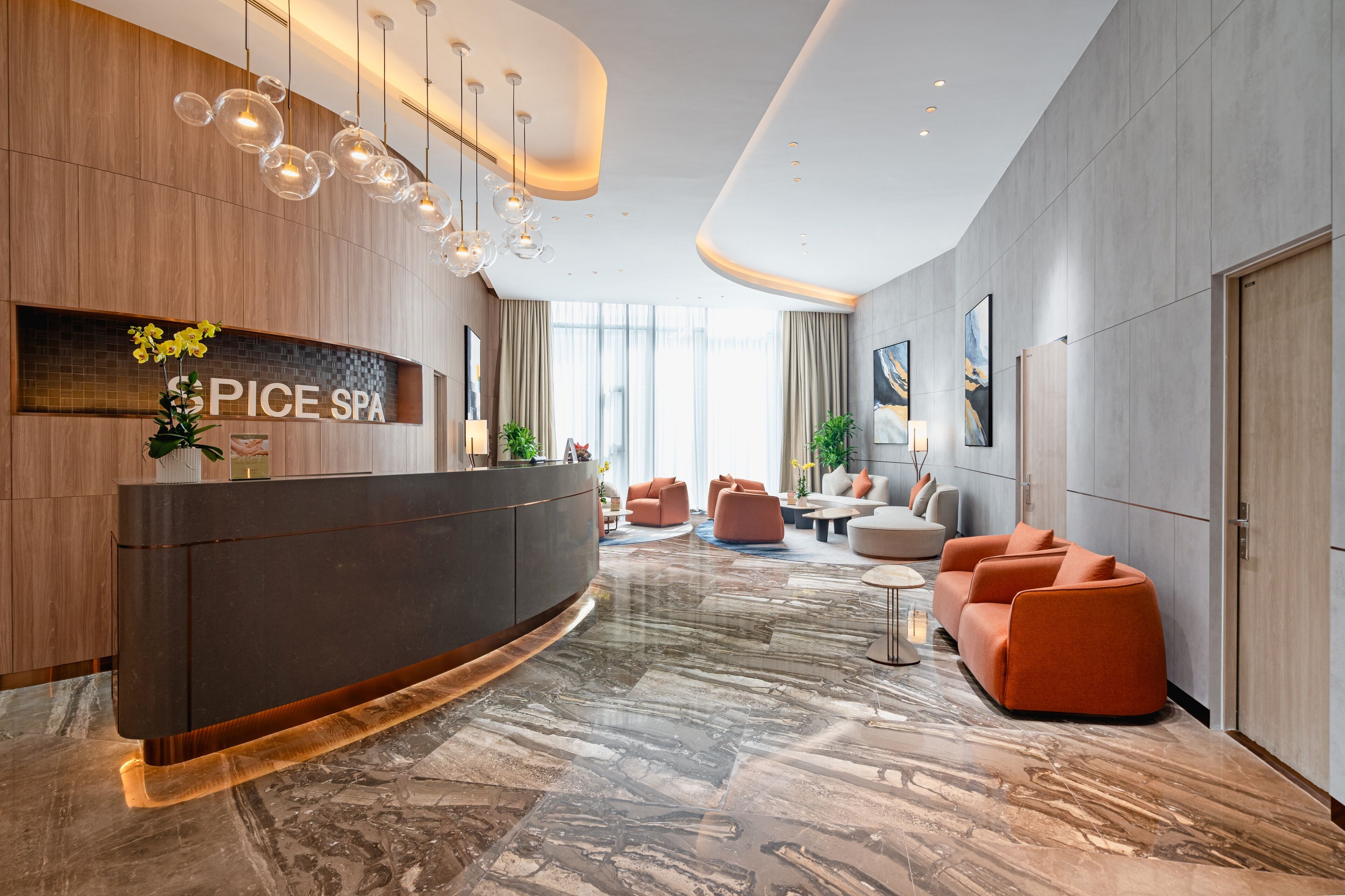 A modern spa lobby with a reception desk, seating area, and large windows.