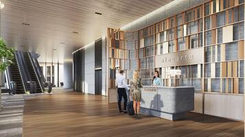 Una moderna hall d'hotel con una reception, una scala e un'ampia parete con motivo decorativo.