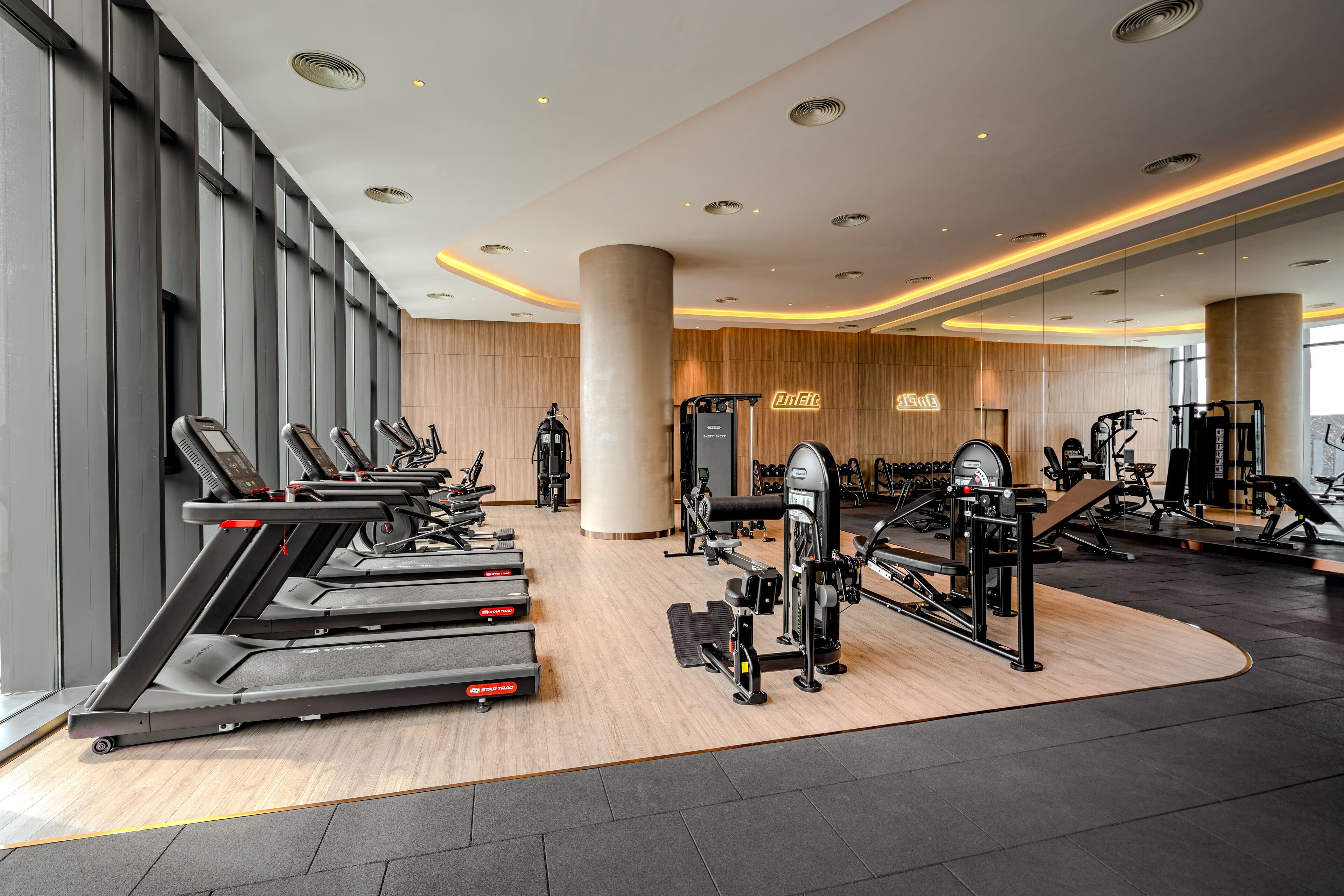 A modern gym with treadmills, weight machines, and a large mirror wall.