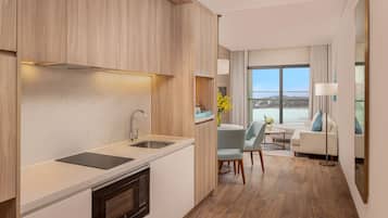 Una cocina moderna con encimera de mármol, armarios de madera y horno empotrado. Cuenta con una zona de comedor con mesa y sillas, y un amplio ventanal con vistas a la ciudad.